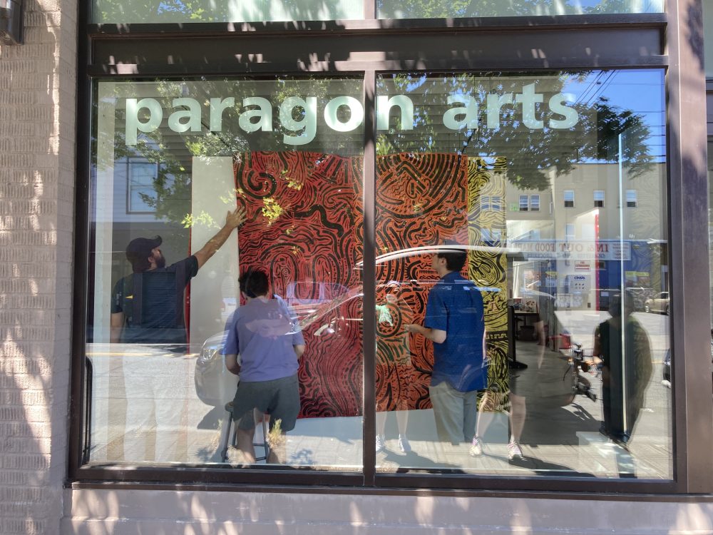 Students hang drawings on the gallery walls.