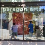Students hang drawings on the gallery walls.