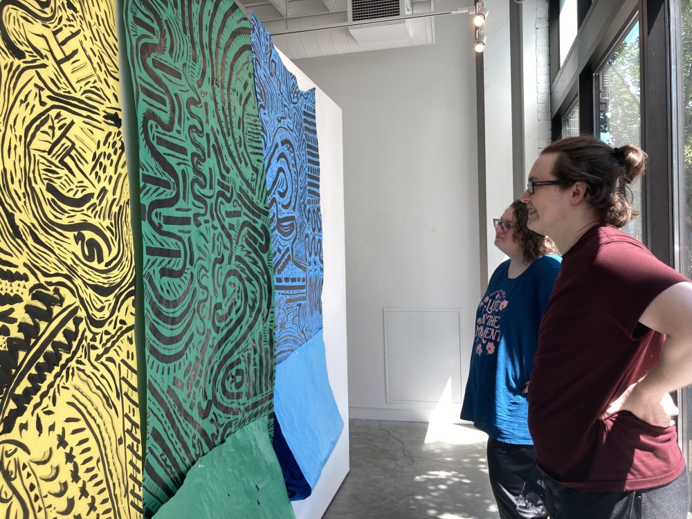 Students hang drawings on the gallery walls.