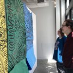 Students hang drawings on the gallery walls.