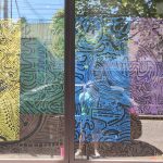 Large-scale black line drawings on colorful paper hanging on the gallery walls.