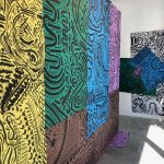 Large-scale black line drawings on colorful paper hanging on the gallery walls.