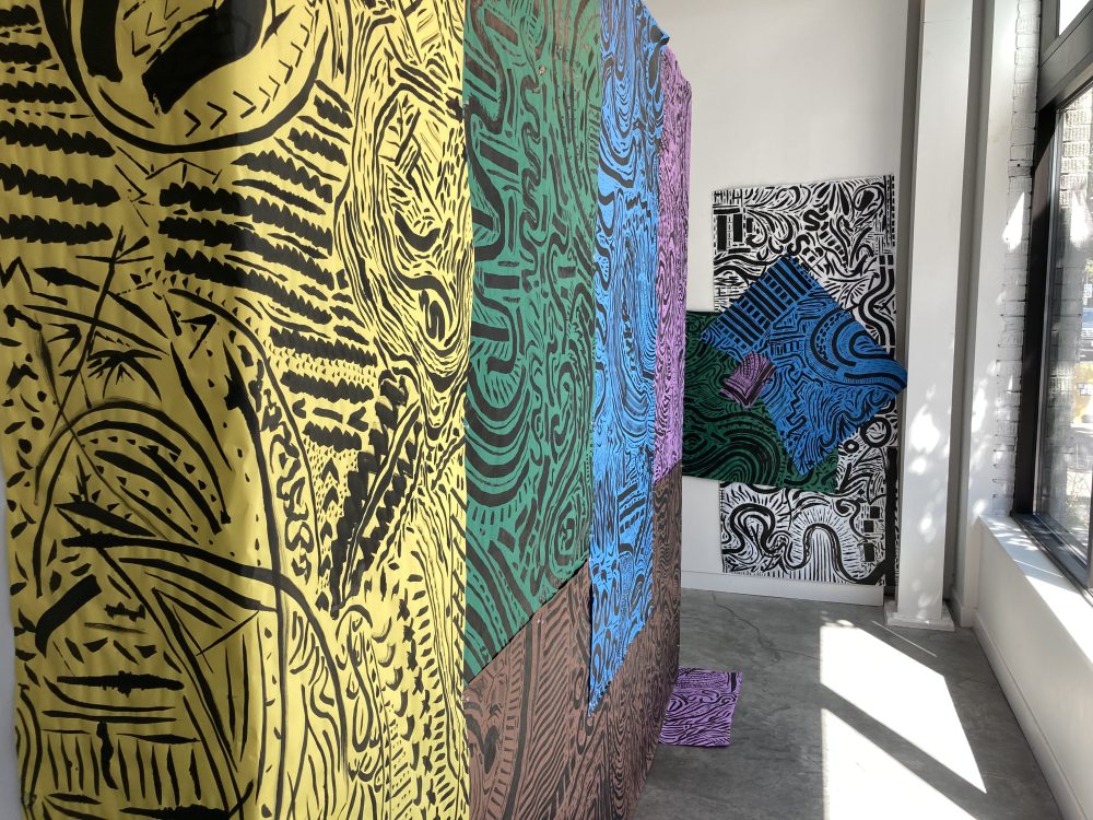 Large-scale black line drawings on colorful paper hanging on the gallery walls.