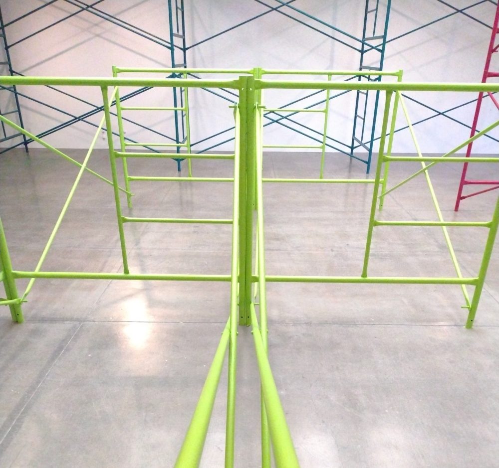 Green, teal and pink scaffolding in a gallery.