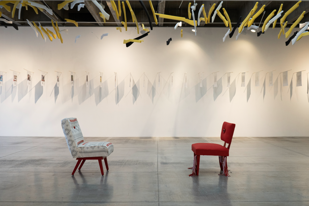 Two chairs in front of a row of flags with white and yellow plastic guns hanging from the roof.