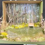 Detail of collage of landscape, city scape, and interior scenes, two-dimensional and three dimensional, installed on a black wall.