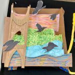 Detail of collage of landscape, city scape, and interior scenes, two-dimensional and three dimensional, installed on a black wall.