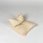Glass white and pink pillow, folded and on the floor.