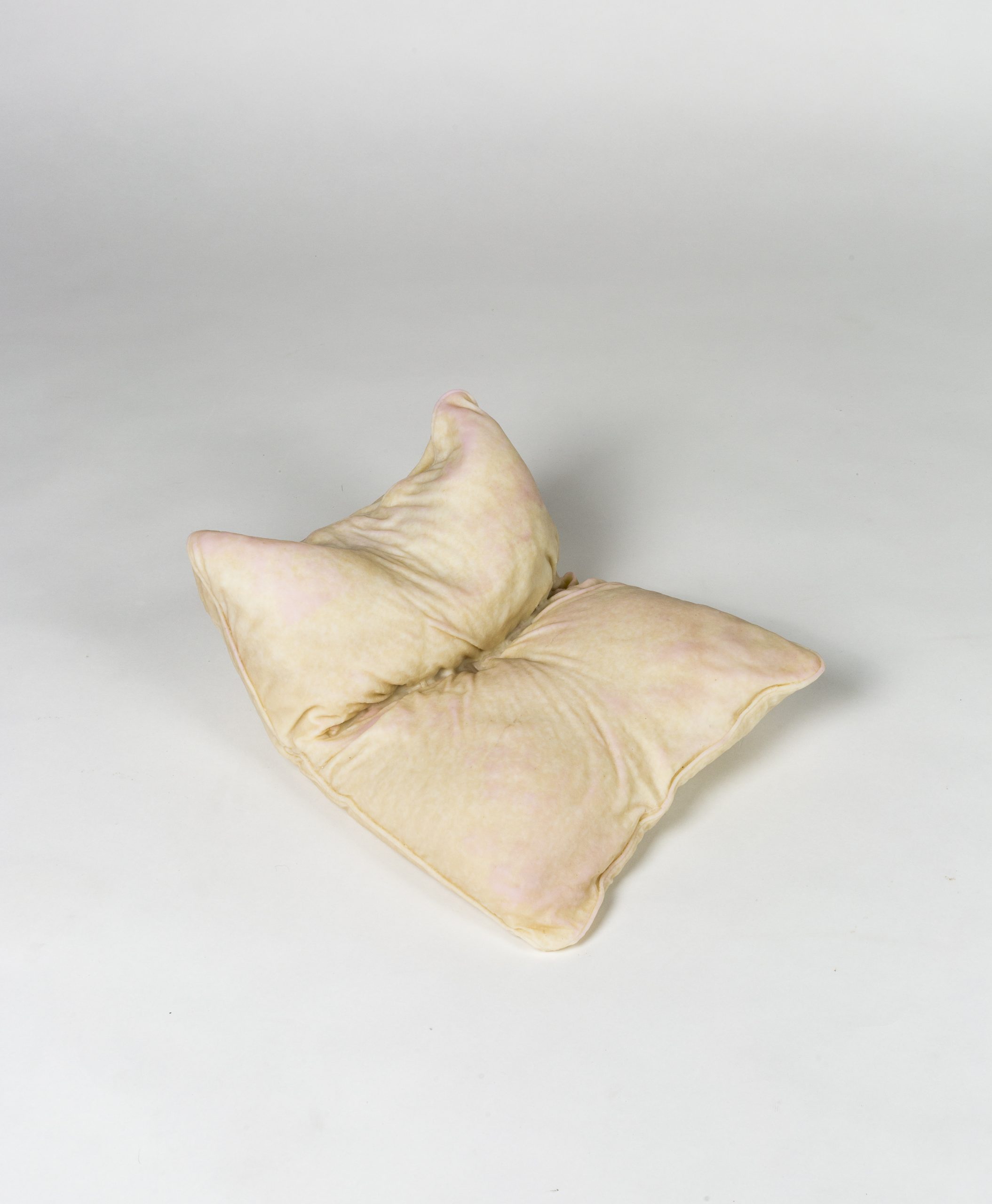 Glass white and pink pillow, folded and on the floor.
