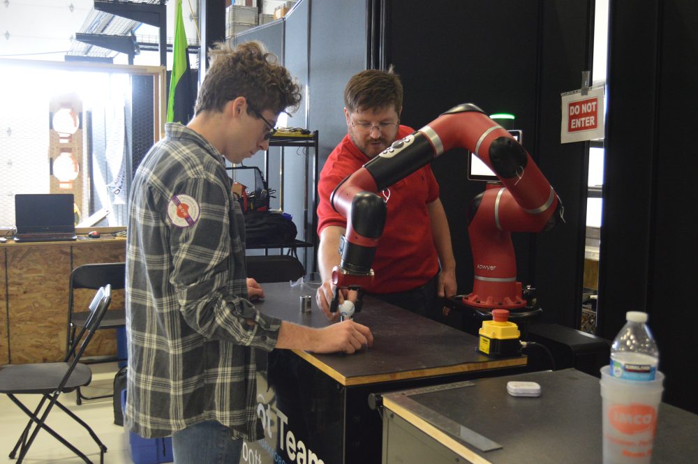 Student participating in robot arm demo.