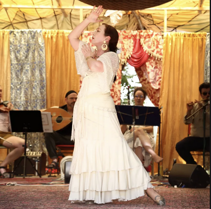 a Flamenco dancer with dark hair and a white dress performing