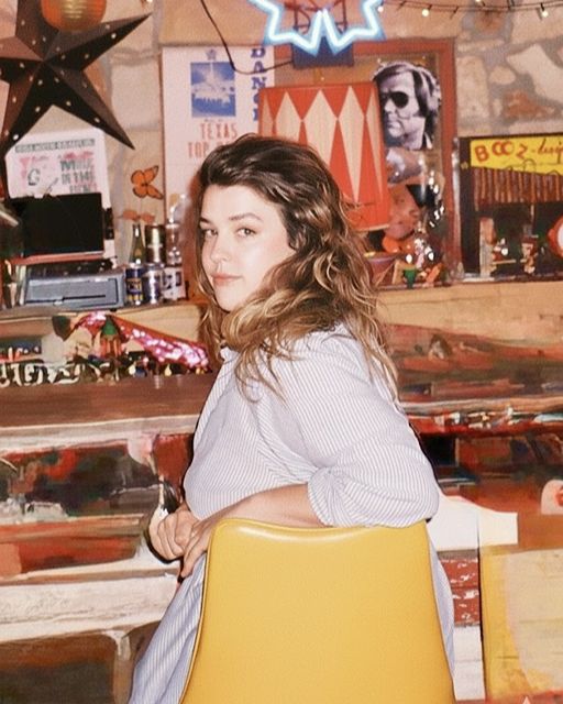Alayna Becker turns back to face the camera from a yellow chair.