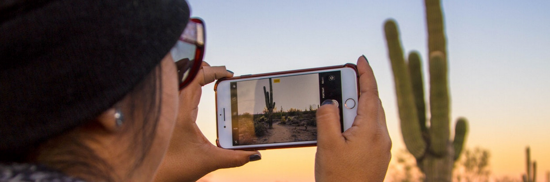 image of a woman recording video of desert with iPhone
