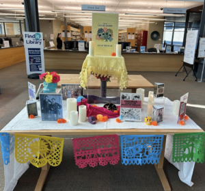 A display for Day of the Dead with candles, skulls, flowers, and images of artists.