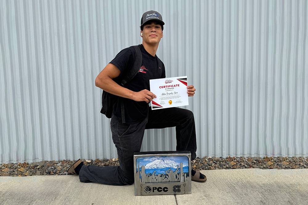 Student holding their project and a certificate
