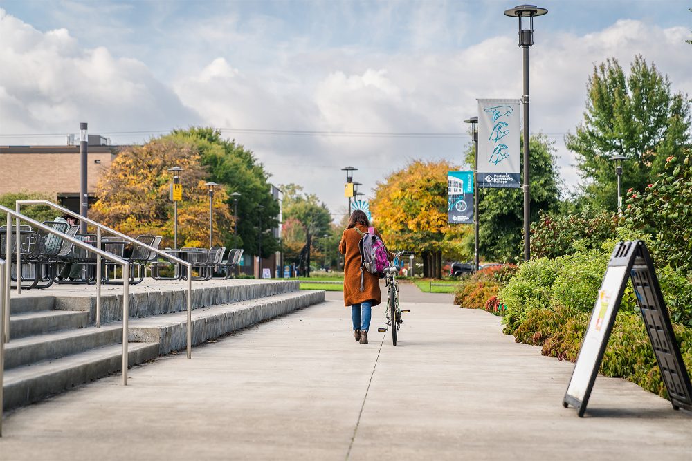 Student walking with a bike on campus