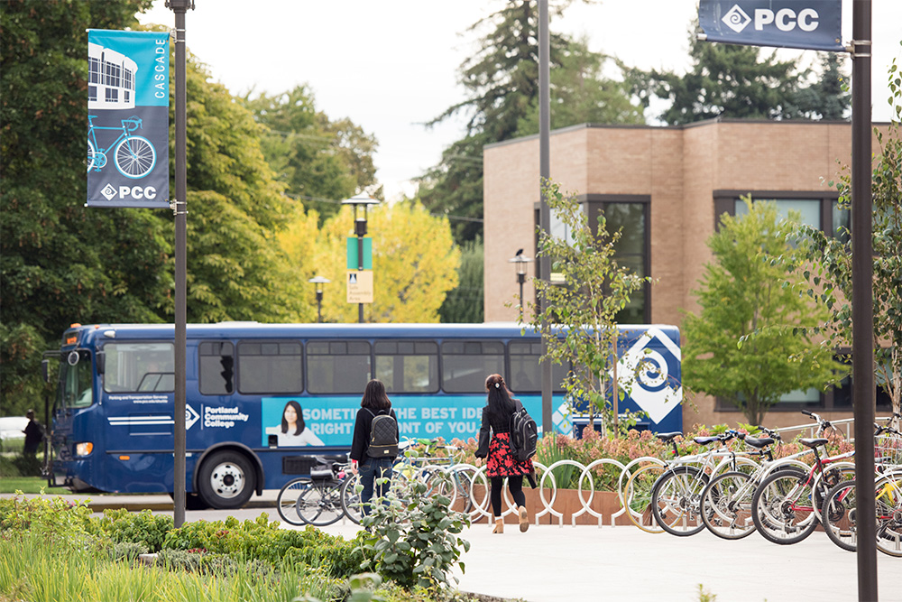 Students walking towards a PCC shuttle past a row of bikes