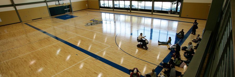 Coach in wheelchair with students sitting on gym floor