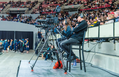 A photo of two video production team members capturing video at Commencement.