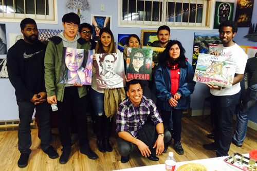 Multicultural Center students holding artwork created by youth from the community