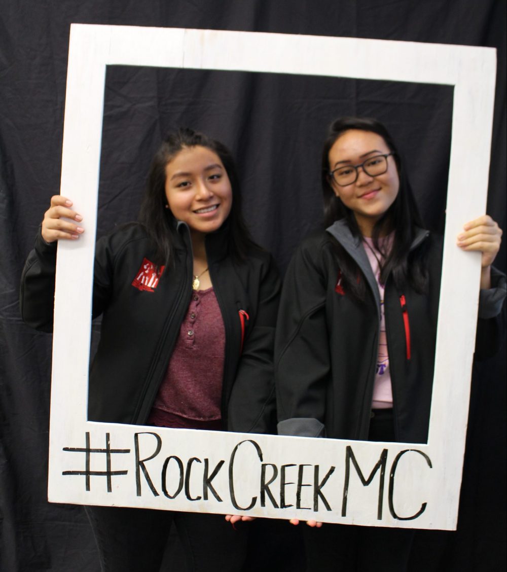 Two students holding up a fake Polaroid frame around their faces with the hashtag #RockCreekMC