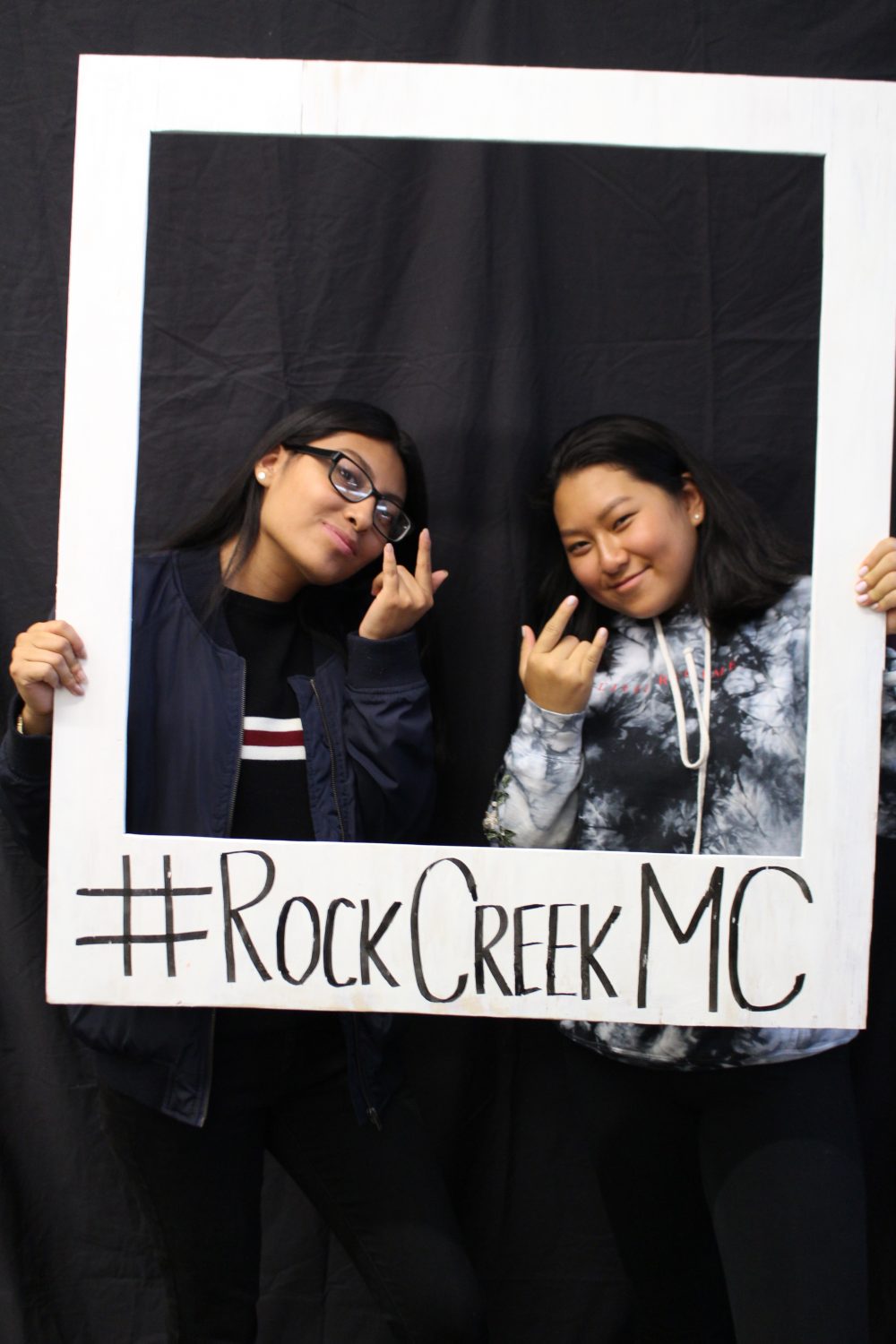 Two students holding up a fake Polaroid frame around their faces with the hashtag #RockCreekMC