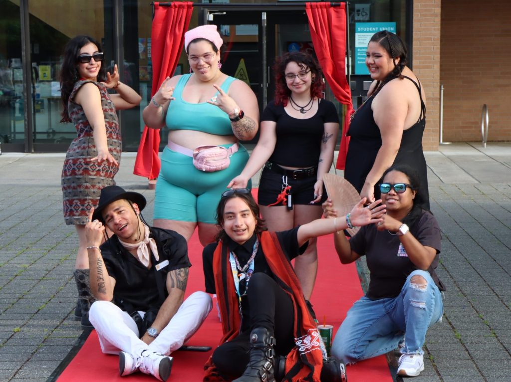 a group of people posing in front of a curtain for a fashion show