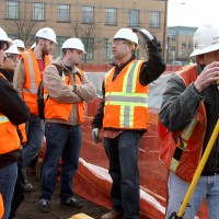 Derrick Beneville, project manager for Hoffman, discusses with the PCC students the kinds of jobs that are on the Cascade construction site. On the right, surveyor Darryl Ming of Ming Surveyors, Inc., scopes out the area.
