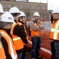 Derrick Beneville, project manager for Hoffman, discusses with the PCC students the kinds of jobs that are on the Cascade construction site. On the right, surveyor Darryl Ming of Ming Surveyors, Inc., scopes out the area.