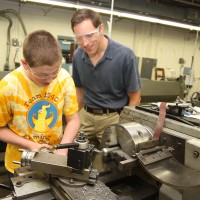 Ben Baldwin, 14, from Catlin Gabel gets a little help from Nathan Beste (right) of FEI Company.
