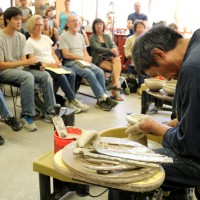 Master potter Kazunao Azuma works the wheel-thrower for the gathered students.
