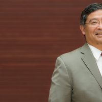 Mark Mitsui against a dark wood background