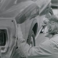 Black and white photo of a student working on a car in the 1970s