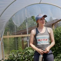 Instructor working with two middle school students in the garden
