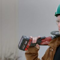 Student wearing a hard hat and holding a hand tool