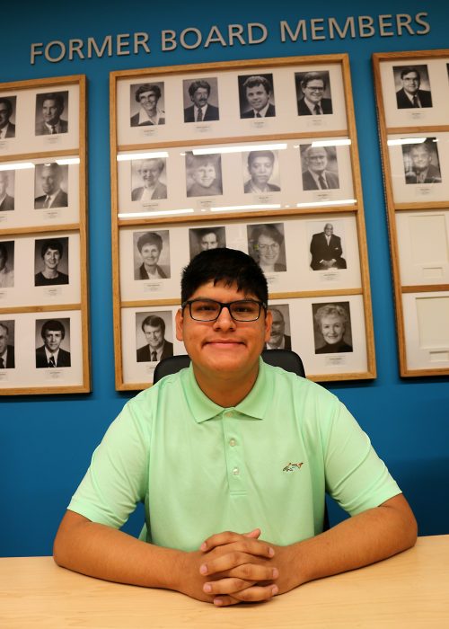 Anthony Schaw in front of past board members photos.