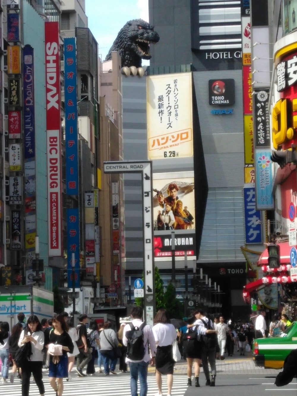 Photo of Godzilla over Toho theater and the busy crowd of Shinjuku.