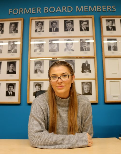 Elsa Van Ornum in front of past board members photos.