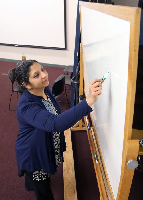 Usha writes on a dry erase board.