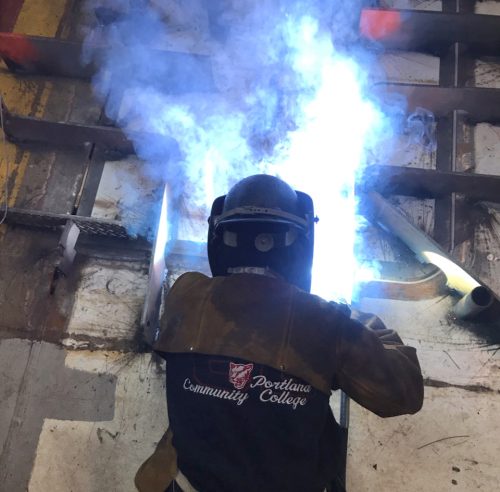 Jess welds with blue flame.