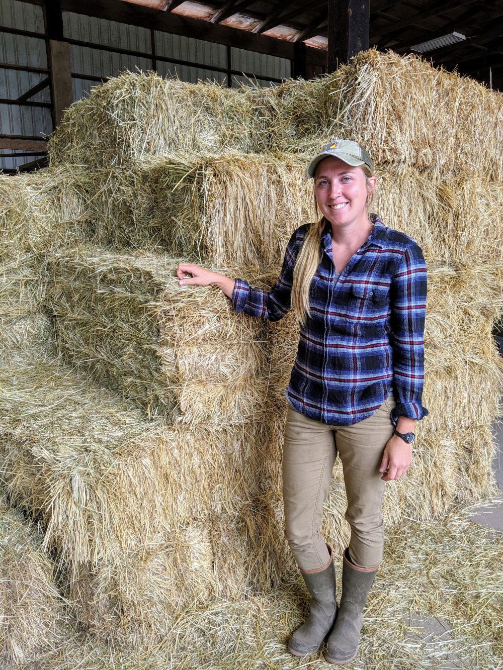 woman standing next to bales of hay