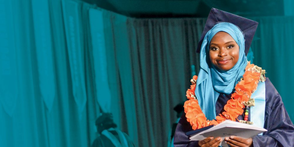 Graduate in front of a turquoise curtain