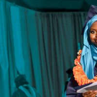 Graduate in front of a turquoise curtain