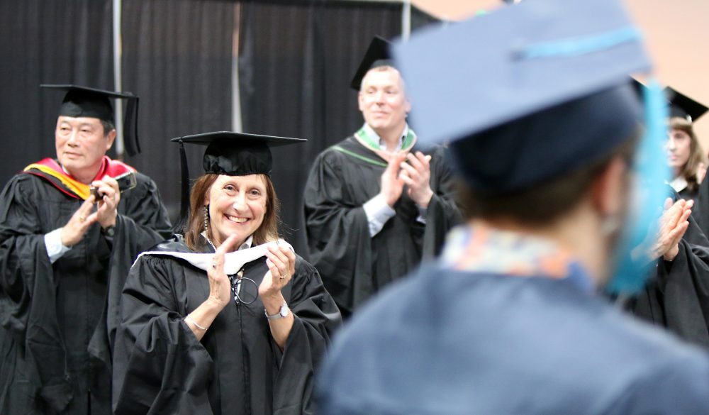 Instructor claps for the graduates.