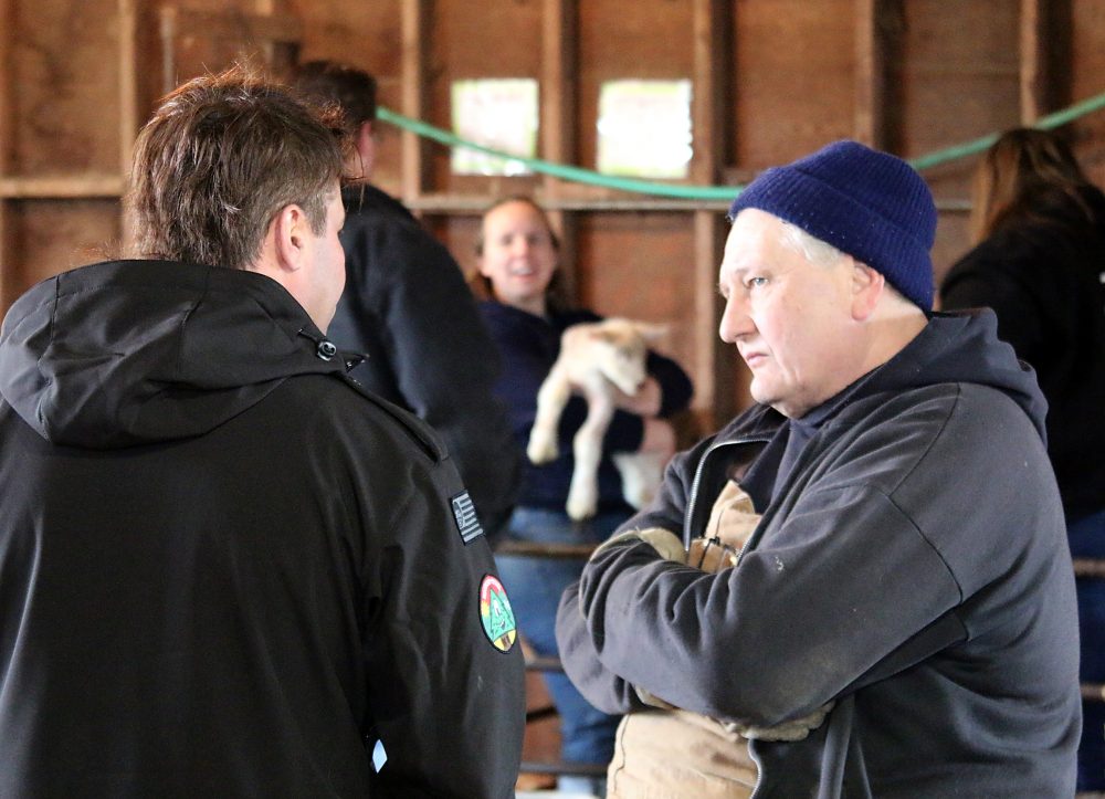 man listening to a student in a barn