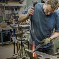 Arnon Kartmazov working in his blacksmithing shop on a red-hot piece of metal