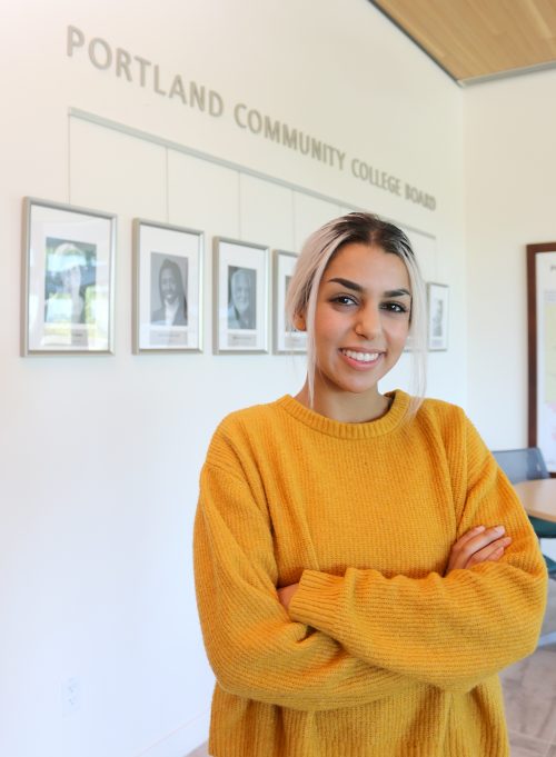 Hannah poses in front of Board photos.