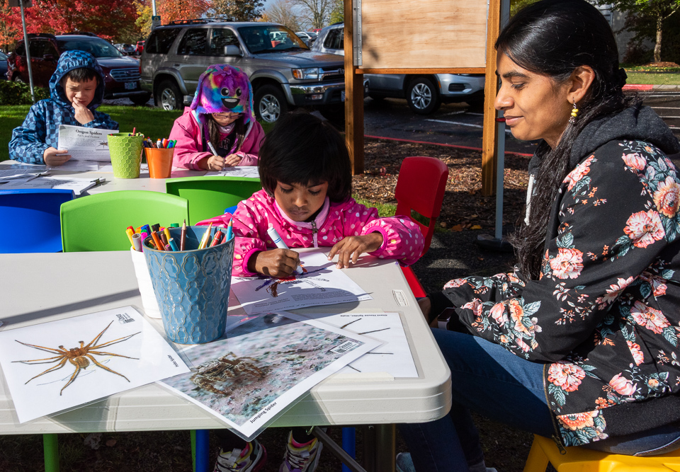 mother watching a daughter color at a table