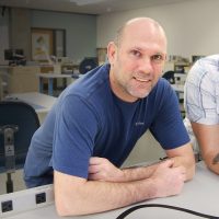 Chris and Mike lean on table