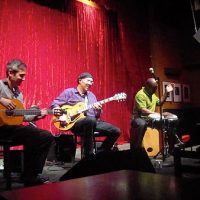 three men playing guitars and drum